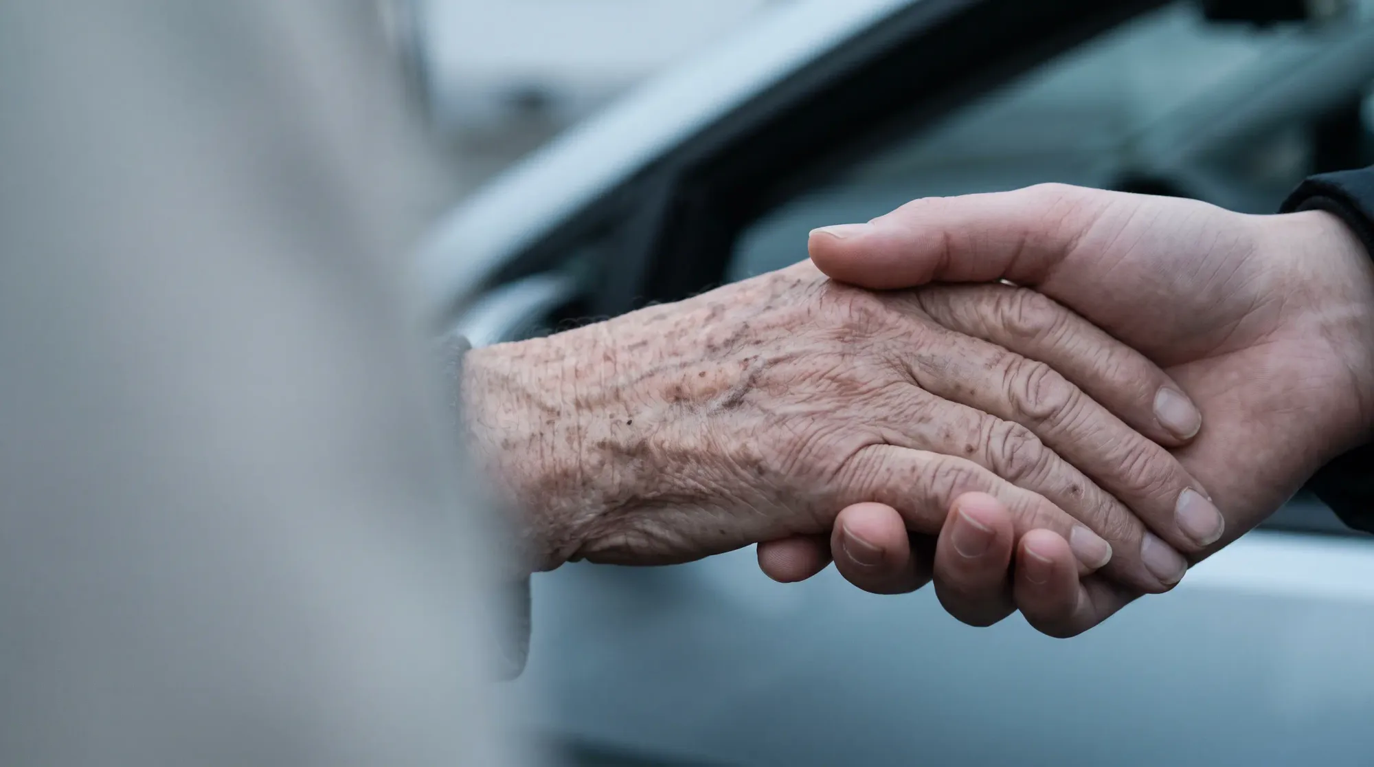 Eine jüngere Hand hält die Hand einer älteren Person